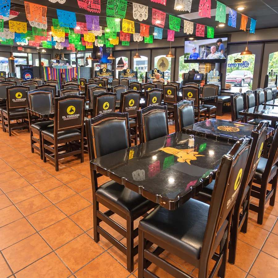 The El Toreado dining room with rows of dark wood tables, branded chairs and TVs